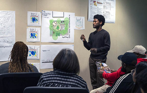 Caleb Austin stands in front of his posters presenting his design to the community.(Photo: Catherine Madsen)